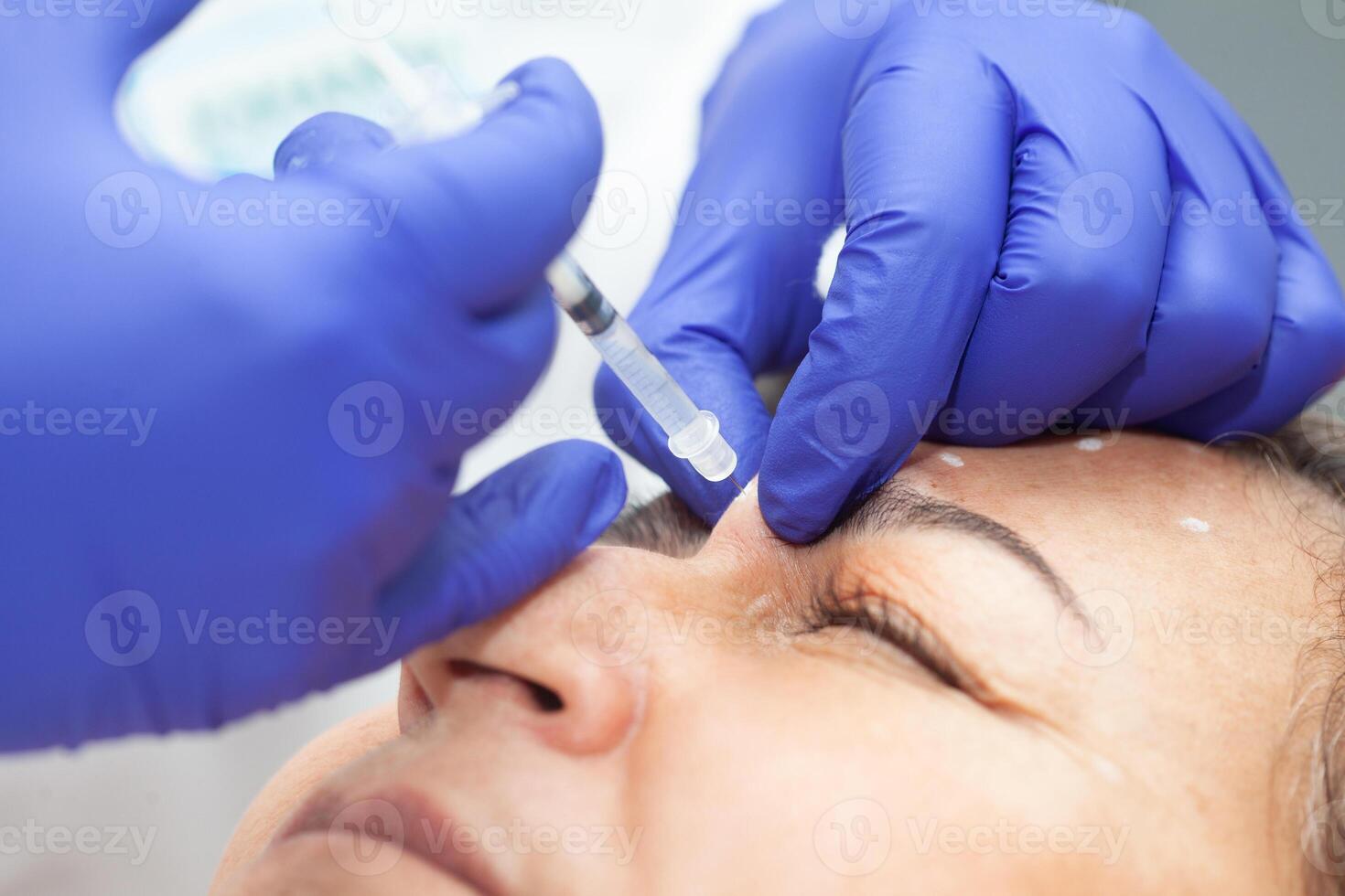 Dermatologist applying Botulinum toxin to a middle age female patient. Aesthetic medicine. photo