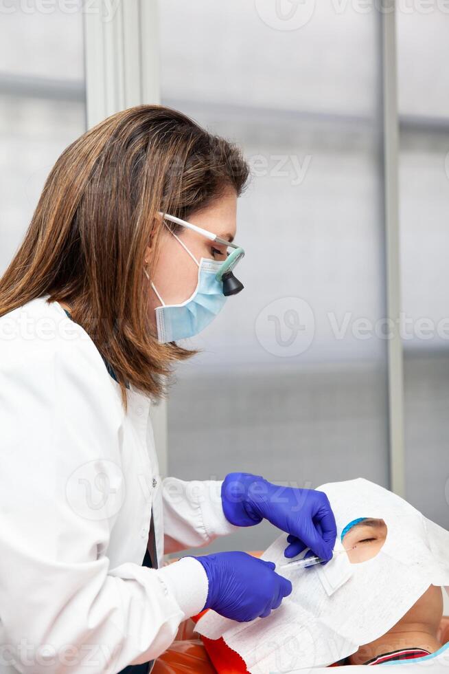 Skin lesion removal procedure. Dermatologist carrying out a removal of benign skin lesion on the face of a young male patient. photo
