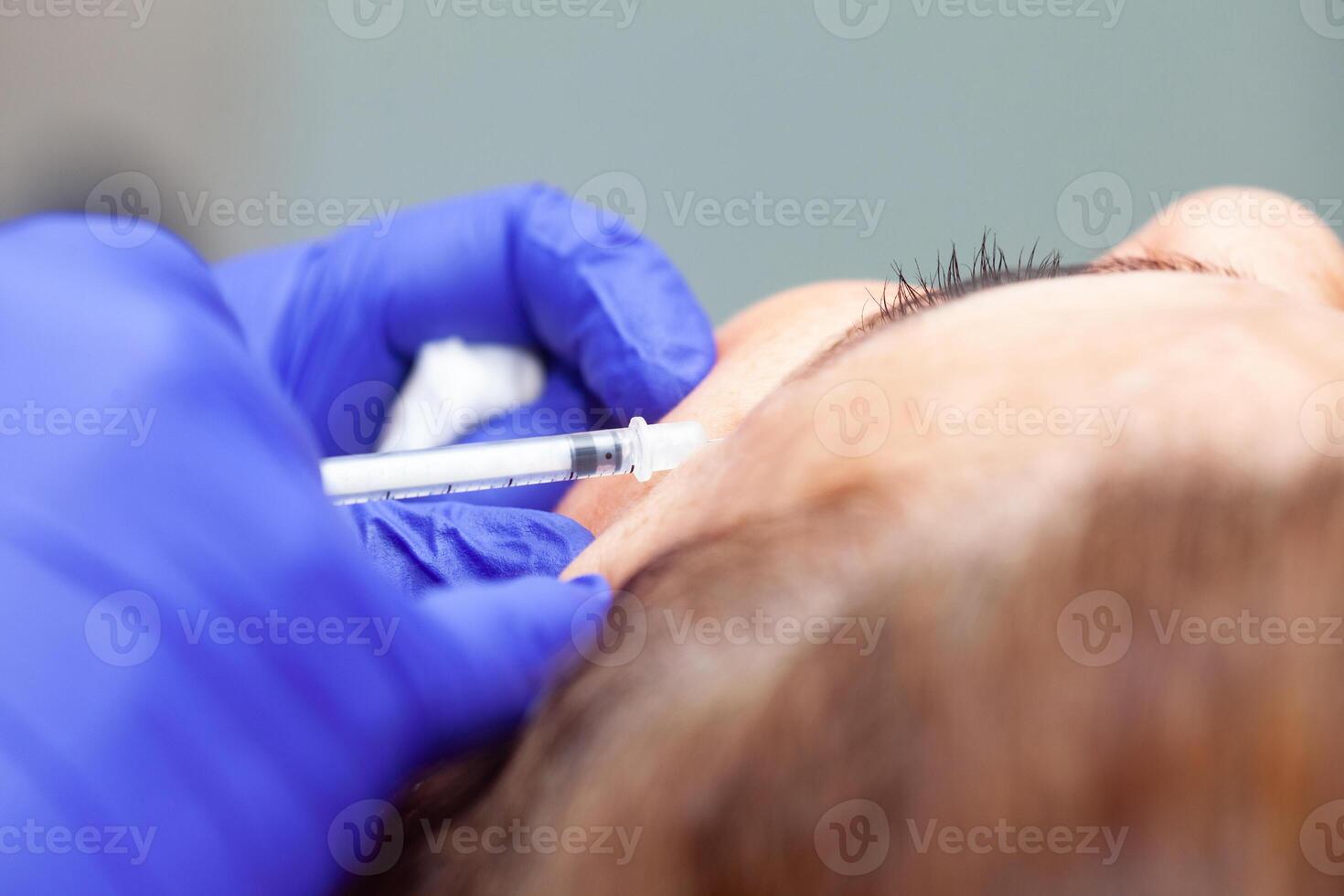 Dermatologist applying Botulinum toxin to a middle age female patient. Aesthetic medicine. photo