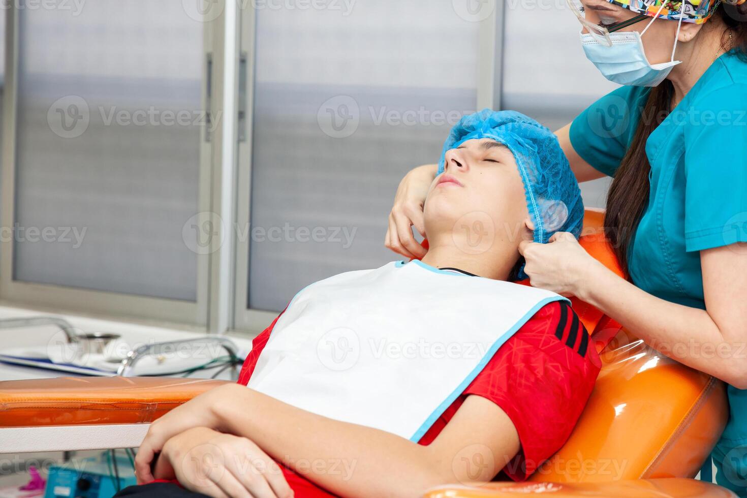 Young male patient being prepared for a skin lesion removal procedure. Dermatologist carrying out a removal of benign skin lesion on the face of a young male patient. photo