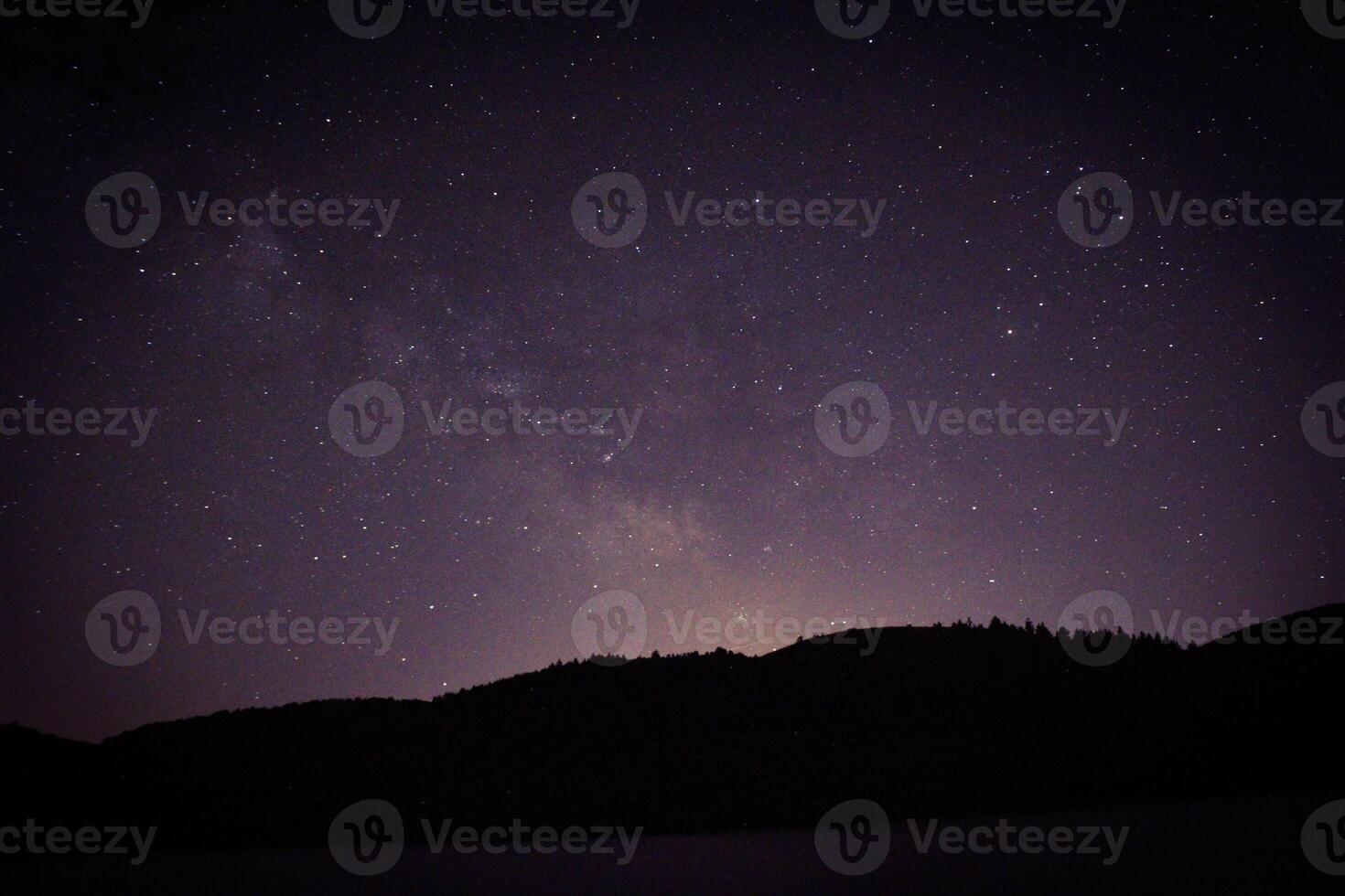Long Exposure of the sky near the forest and lake at night time. Stars and galaxy. astro photography photo