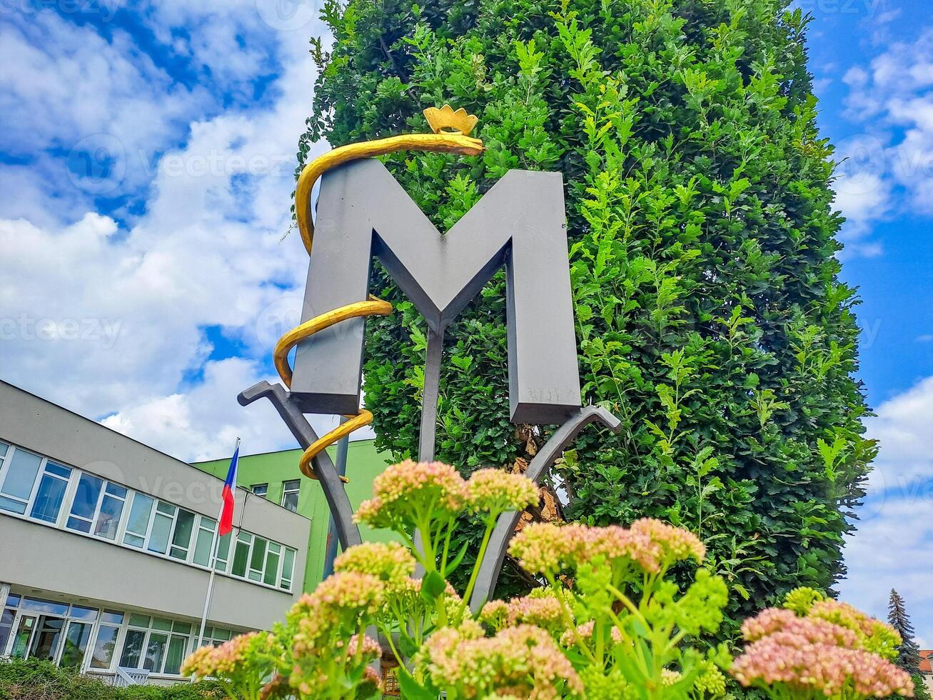 Ornate decoration of fence with artistic monogram, letter M with a snake. Czech photo