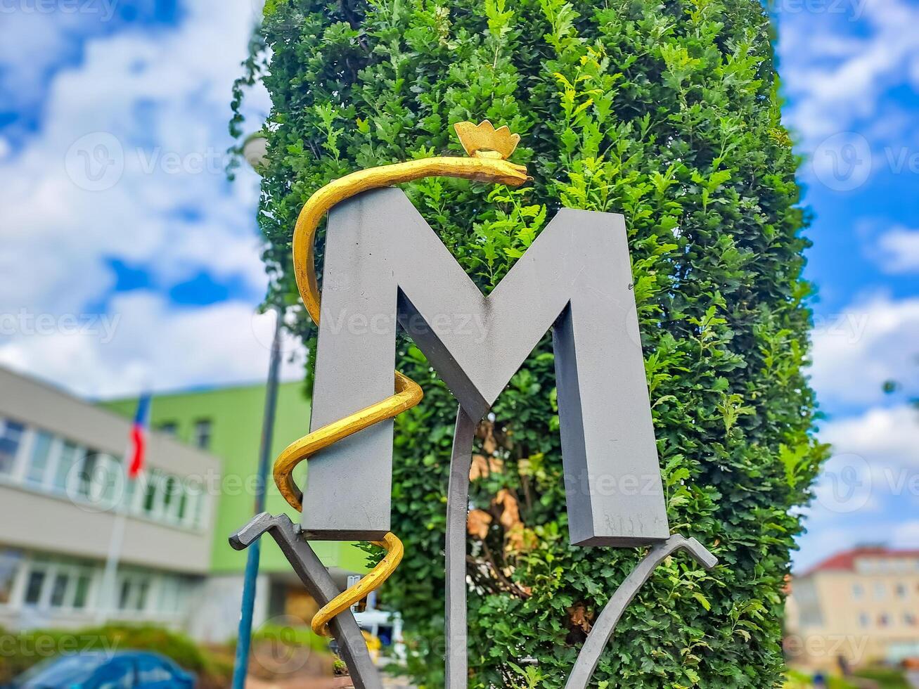 Ornate decoration of fence with artistic monogram, letter M with a snake. Czech photo