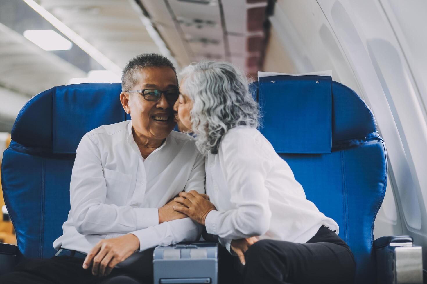 A mature couple enjoys a plane ride sitting near the window. They looked out into the sky. Immerse yourself in the scenery and excitement of the journey. To create precious memories together photo