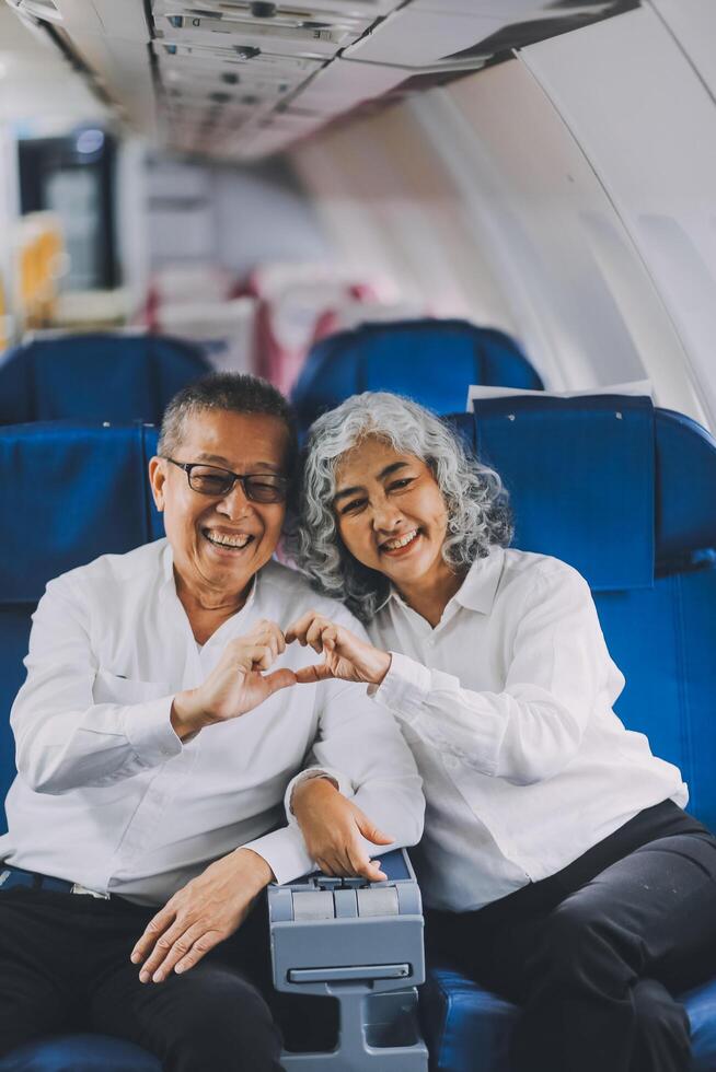 A mature couple enjoys a plane ride sitting near the window. They looked out into the sky. Immerse yourself in the scenery and excitement of the journey. To create precious memories together photo