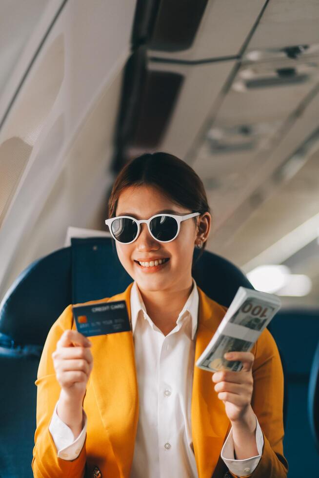 A young Asian woman, seated as an airplane passenger, contemplates dollar bills, reflecting on lucrative opportunities and aspirations towards billionaire status. photo