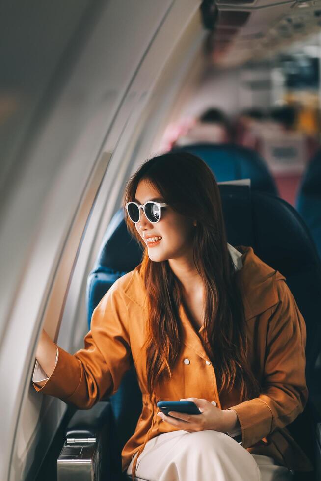 Joyful asian woman sits in the airplane and using tablet while go to travel photo