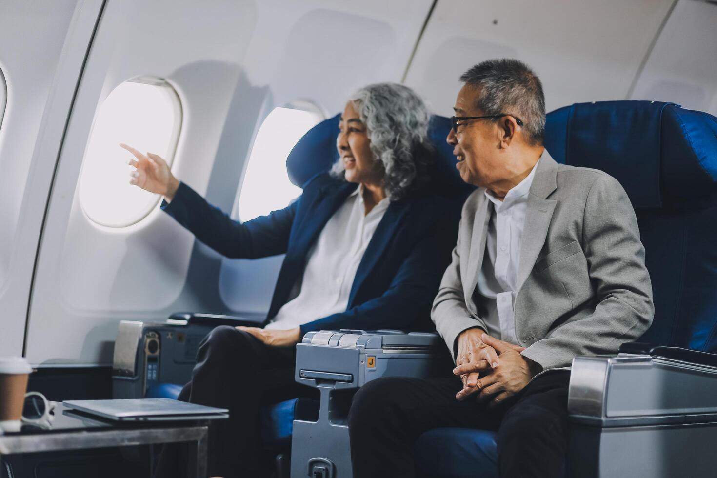 A mature couple enjoys a plane ride sitting near the window. They looked out into the sky. Immerse yourself in the scenery and excitement of the journey. To create precious memories together photo