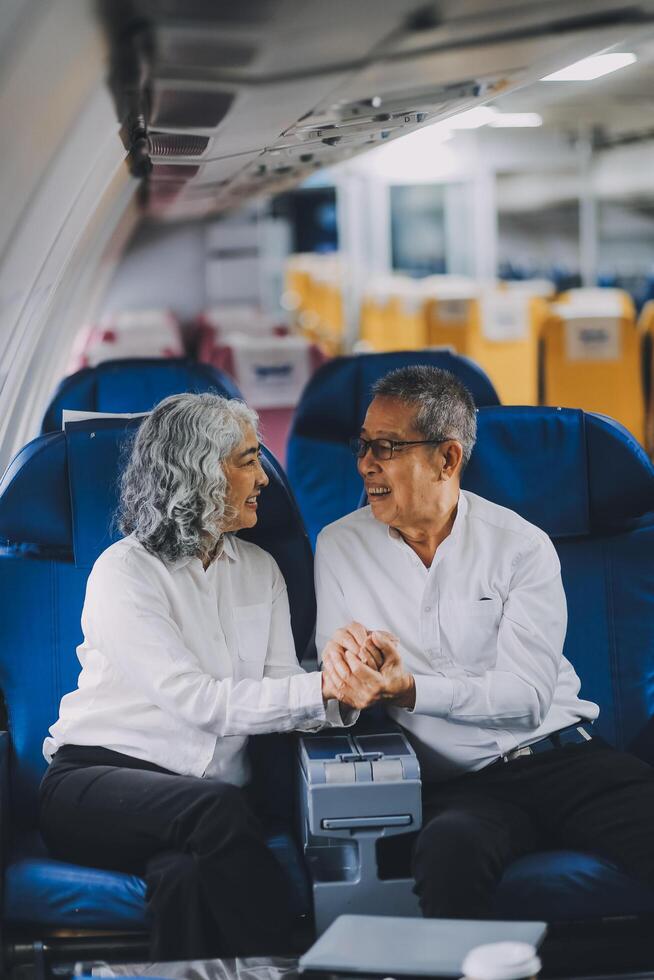 A mature couple enjoys a plane ride sitting near the window. They looked out into the sky. Immerse yourself in the scenery and excitement of the journey. To create precious memories together photo