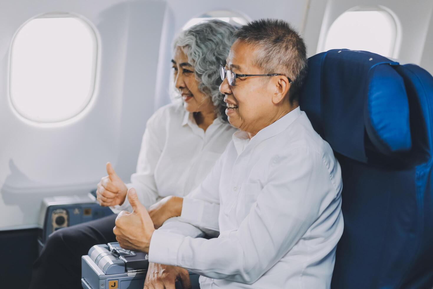 A mature couple enjoys a plane ride sitting near the window. They looked out into the sky. Immerse yourself in the scenery and excitement of the journey. To create precious memories together photo