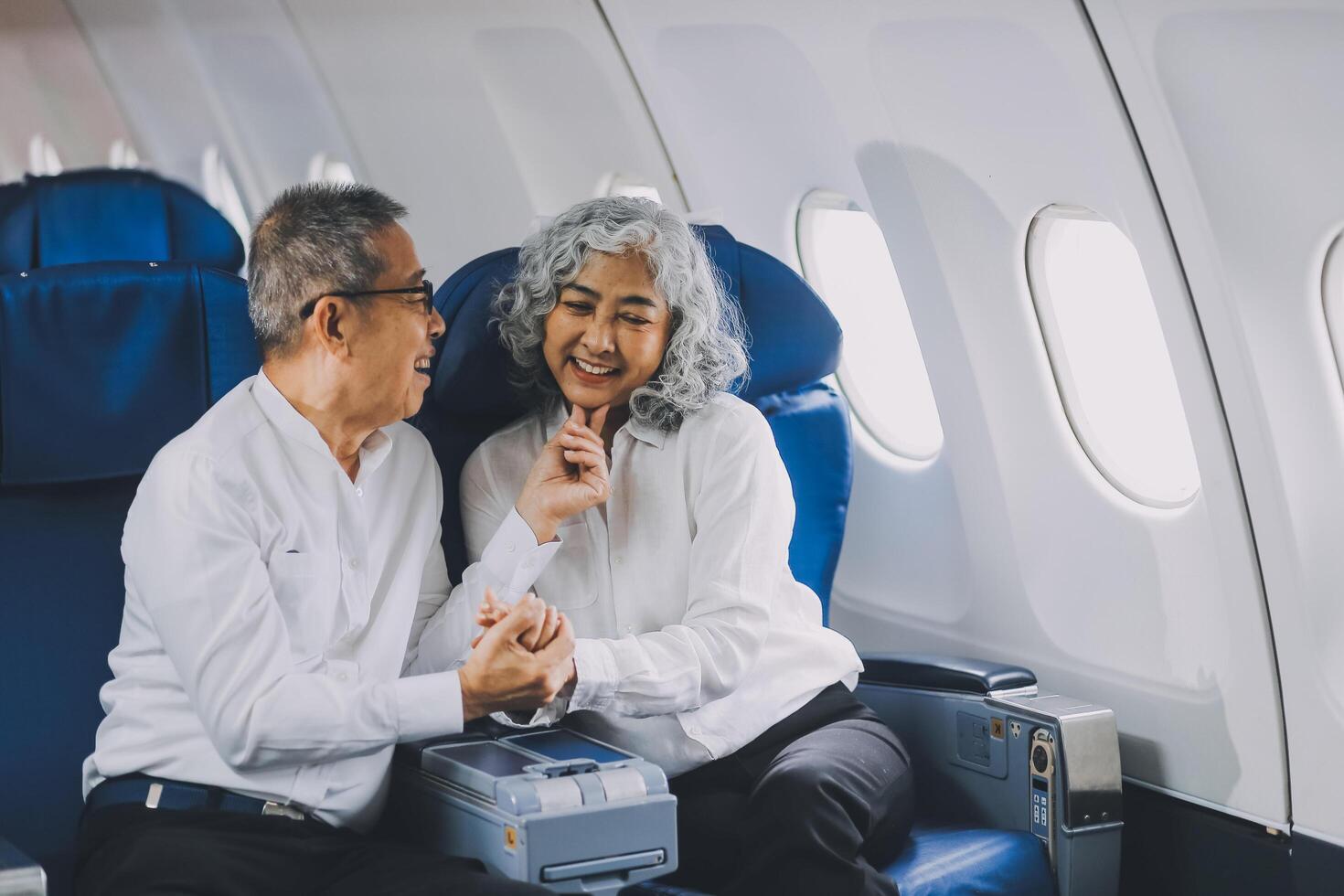 A mature couple enjoys a plane ride sitting near the window. They looked out into the sky. Immerse yourself in the scenery and excitement of the journey. To create precious memories together photo