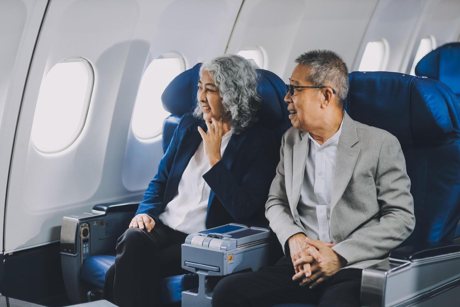 A mature couple enjoys a plane ride sitting near the window. They looked out into the sky. Immerse yourself in the scenery and excitement of the journey. To create precious memories together photo