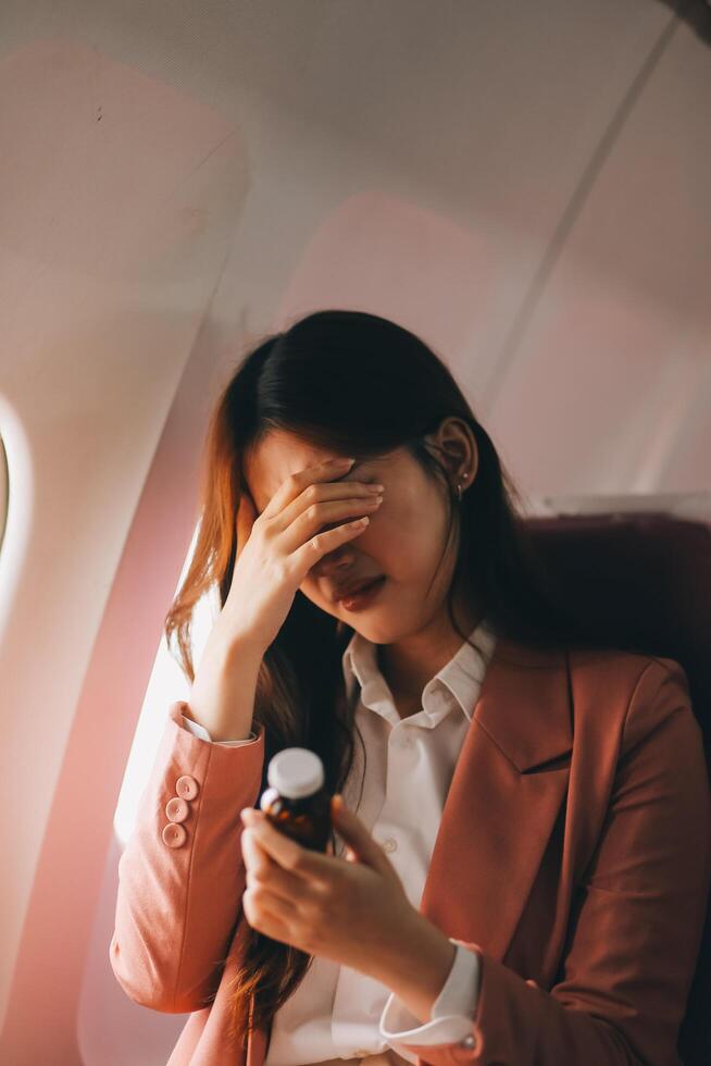 Tired asian woman with headache feeling sick while sitting in the airplane , Passengers near the window. photo