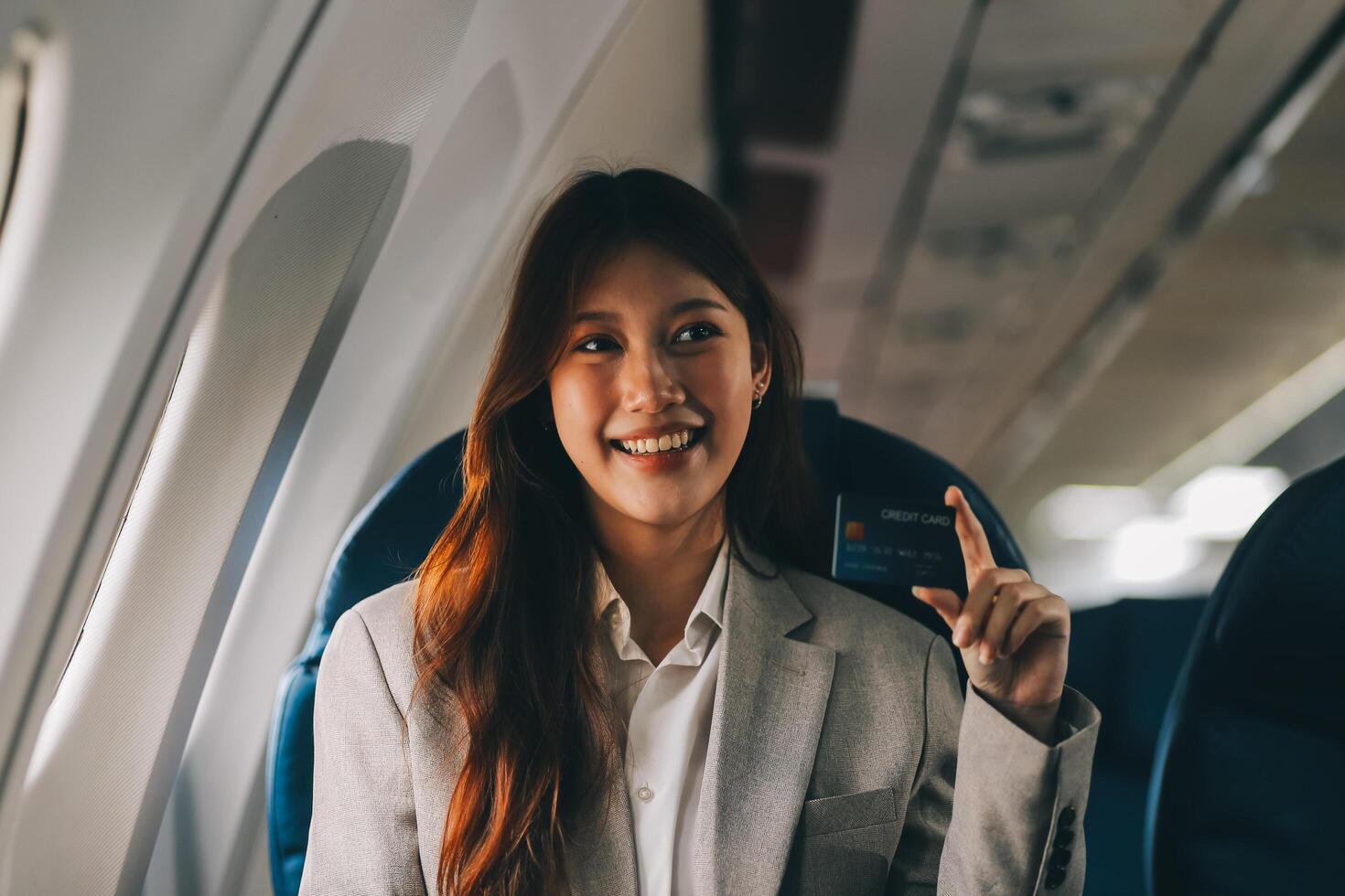 Young businesswoman holding credit card near blurred devices in private plane photo