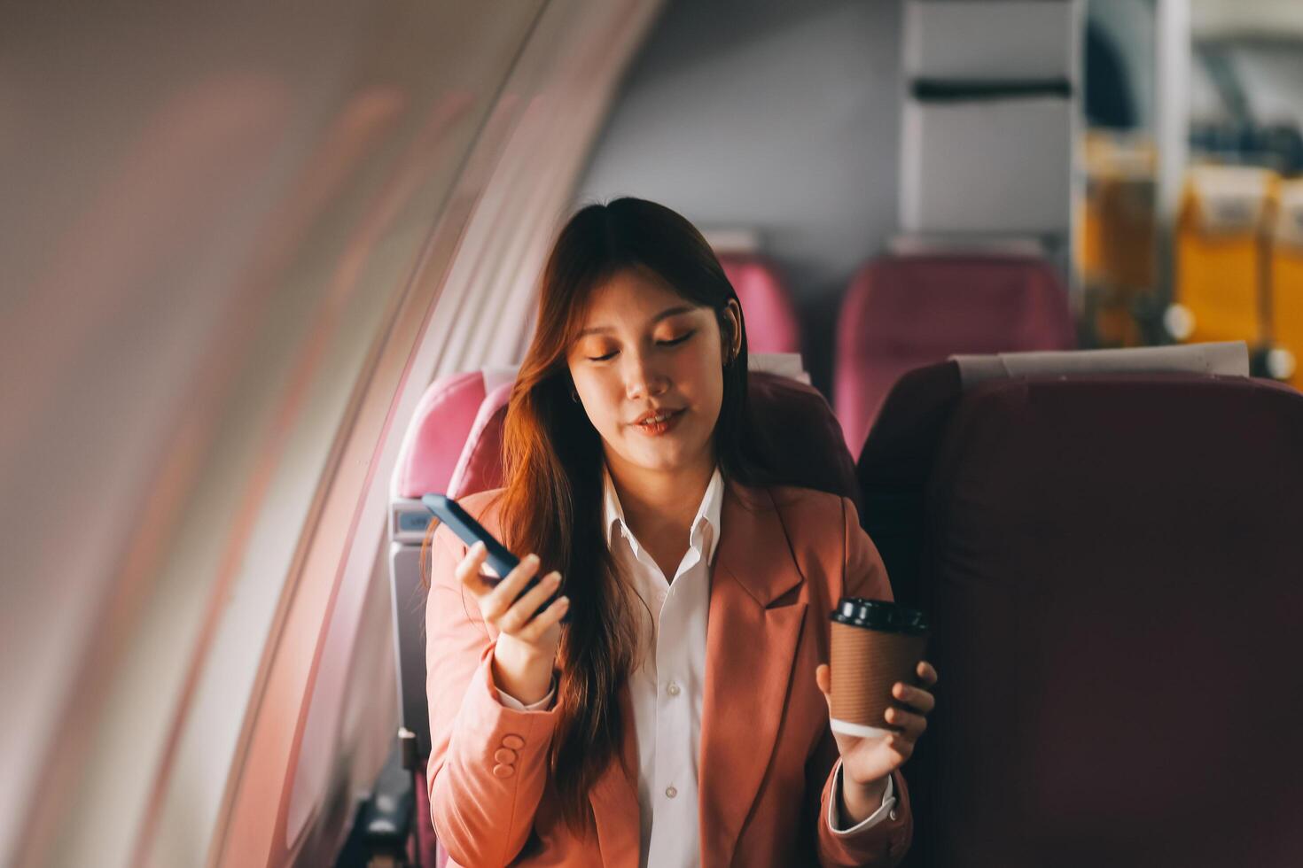 Attractive Asian female passenger of airplane sitting in comfortable seat while working laptop and tablet with mock up area using wireless connection. Travel in style, work with grace. photo