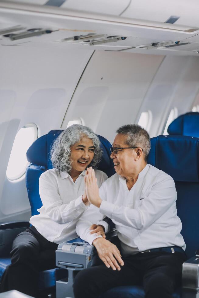 A mature couple enjoys a plane ride sitting near the window. They looked out into the sky. Immerse yourself in the scenery and excitement of the journey. To create precious memories together photo