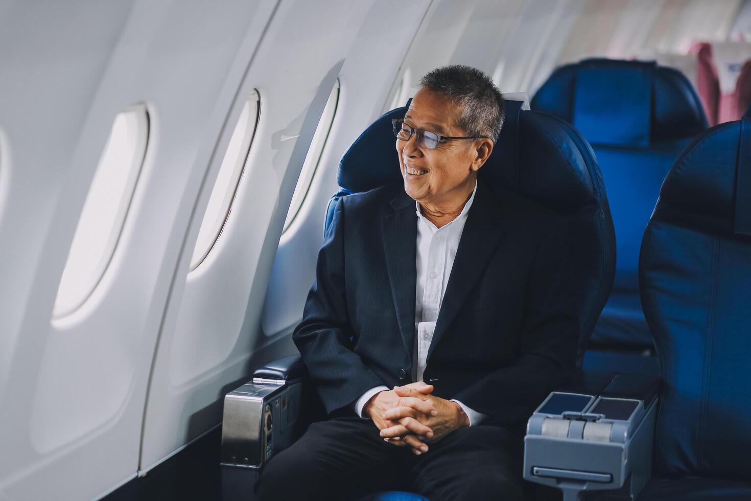Attractive Asian male passenger of airplane sitting in comfortable seat while working laptop and tablet with mock up area using wireless connection. Travel in style, work with grace. photo