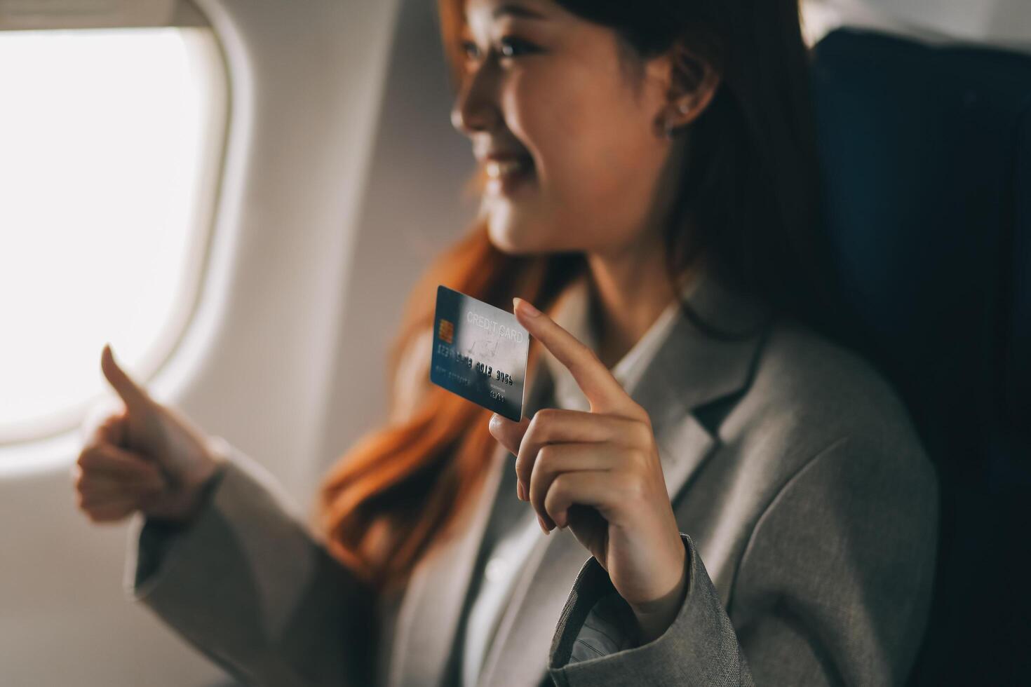 Young businesswoman holding credit card near blurred devices in private plane photo