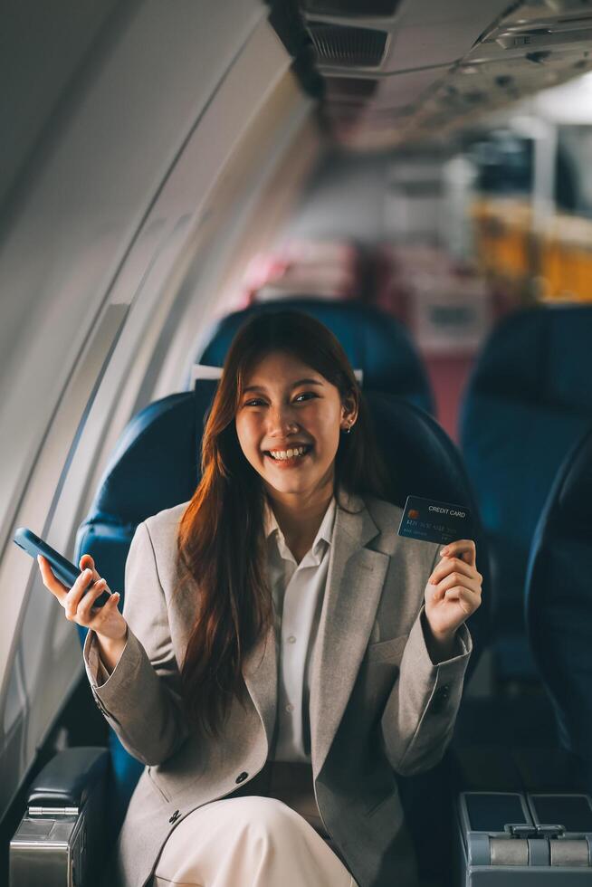 Young businesswoman holding credit card near blurred devices in private plane photo