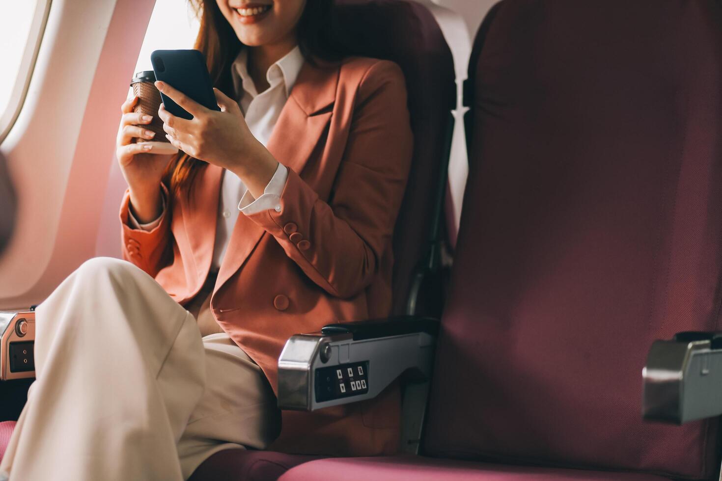 Attractive Asian female passenger of airplane sitting in comfortable seat while working laptop and tablet with mock up area using wireless connection. Travel in style, work with grace. photo