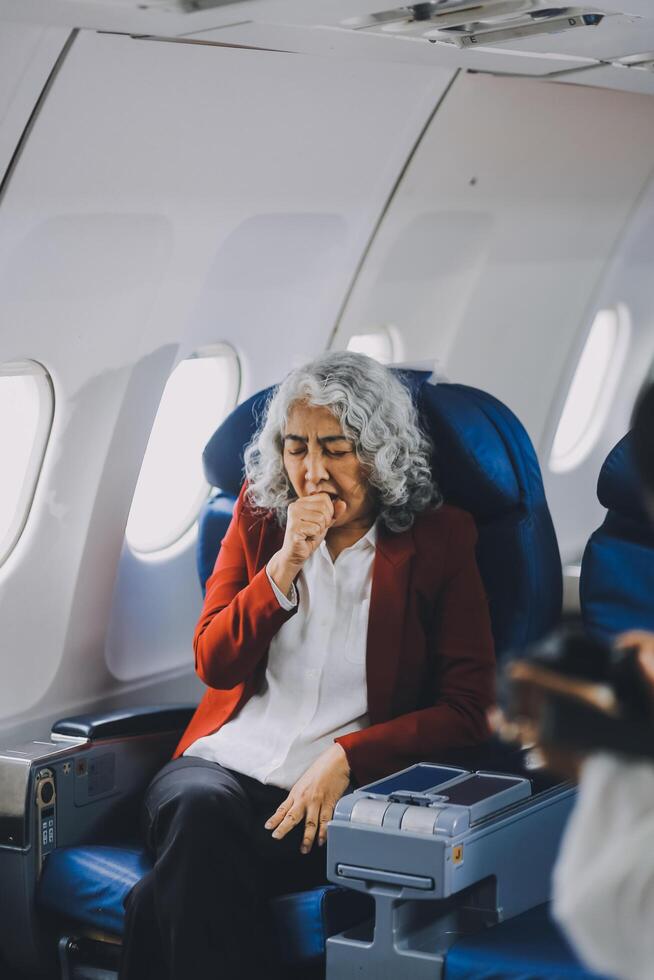 Mature with headache with nausea feeling sick while sitting in the airplane , Passengers near the window. photo