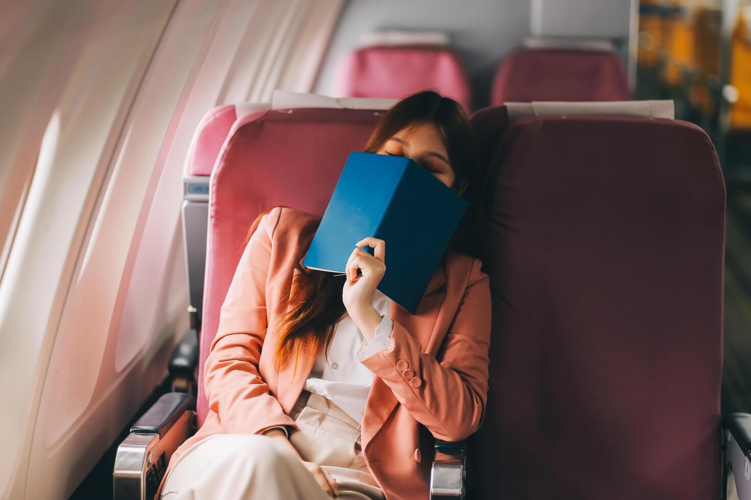 Tired asian woman with headache feeling sick while sitting in the airplane , Passengers near the window. photo