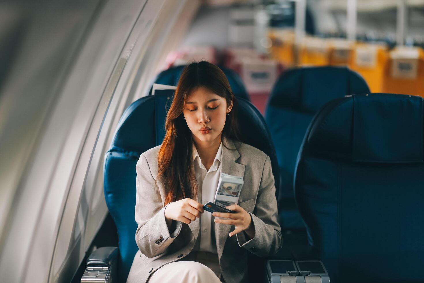 Young businesswoman holding credit card near blurred devices in private plane photo