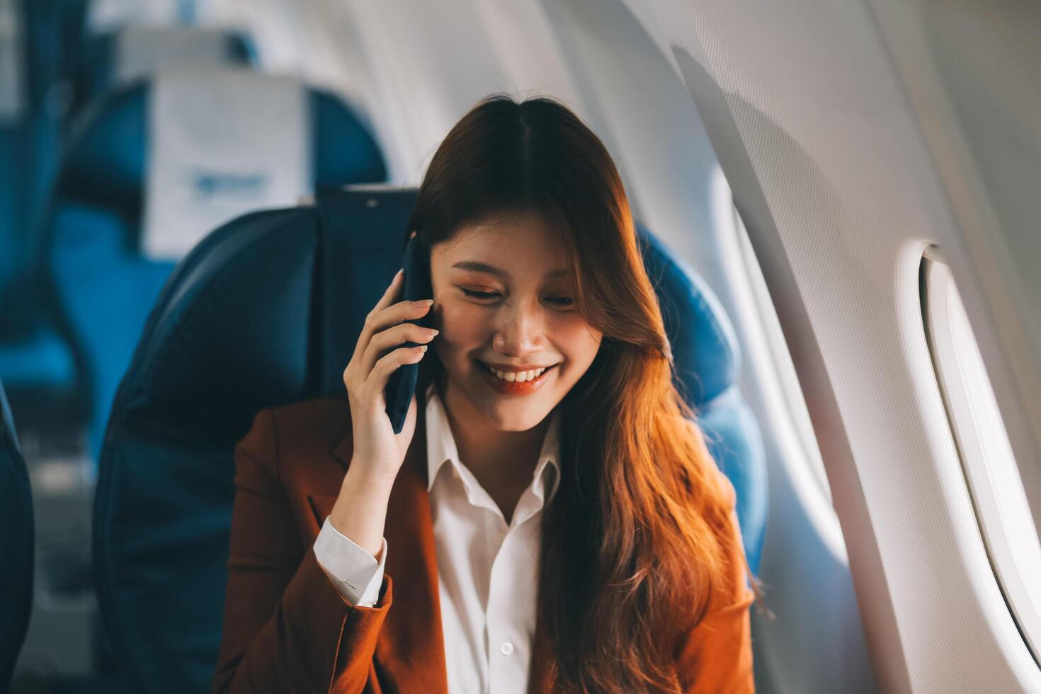 Young Asian executive excels in first class, multitasking with digital tablet, laptop and smartphone. Travel in style, work with grace. photo