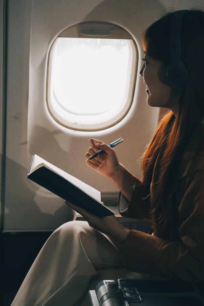 A young Asian woman, seated as an airplane passenger, contemplates dollar bills, reflecting on lucrative opportunities and aspirations towards billionaire status. photo