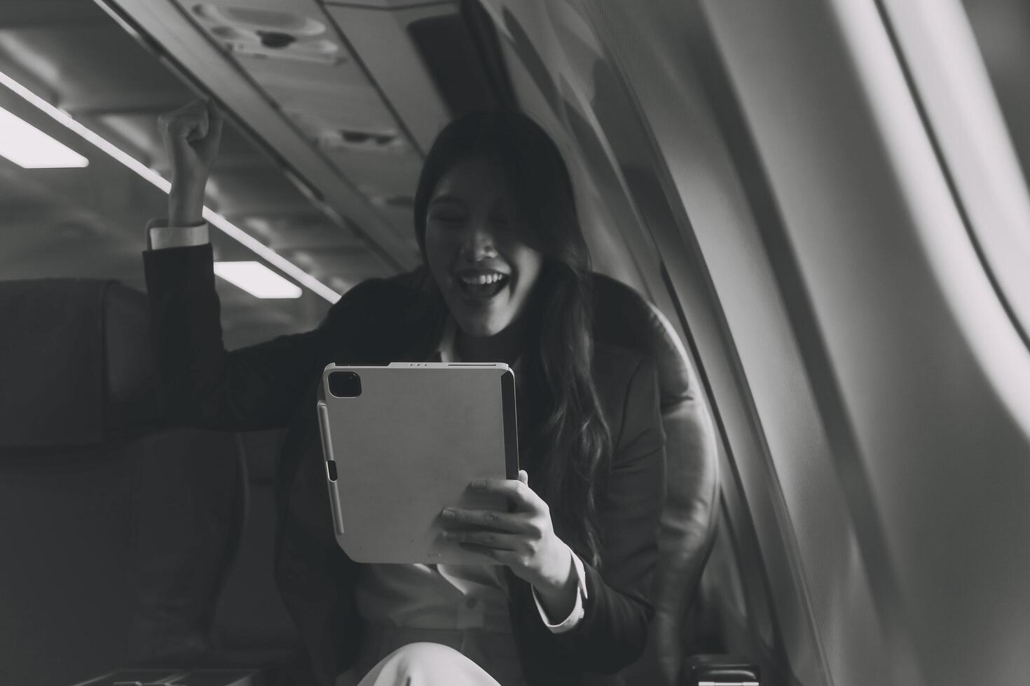 Young Asian executive excels in first class, multitasking with digital tablet, laptop and smartphone. Travel in style, work with grace. photo