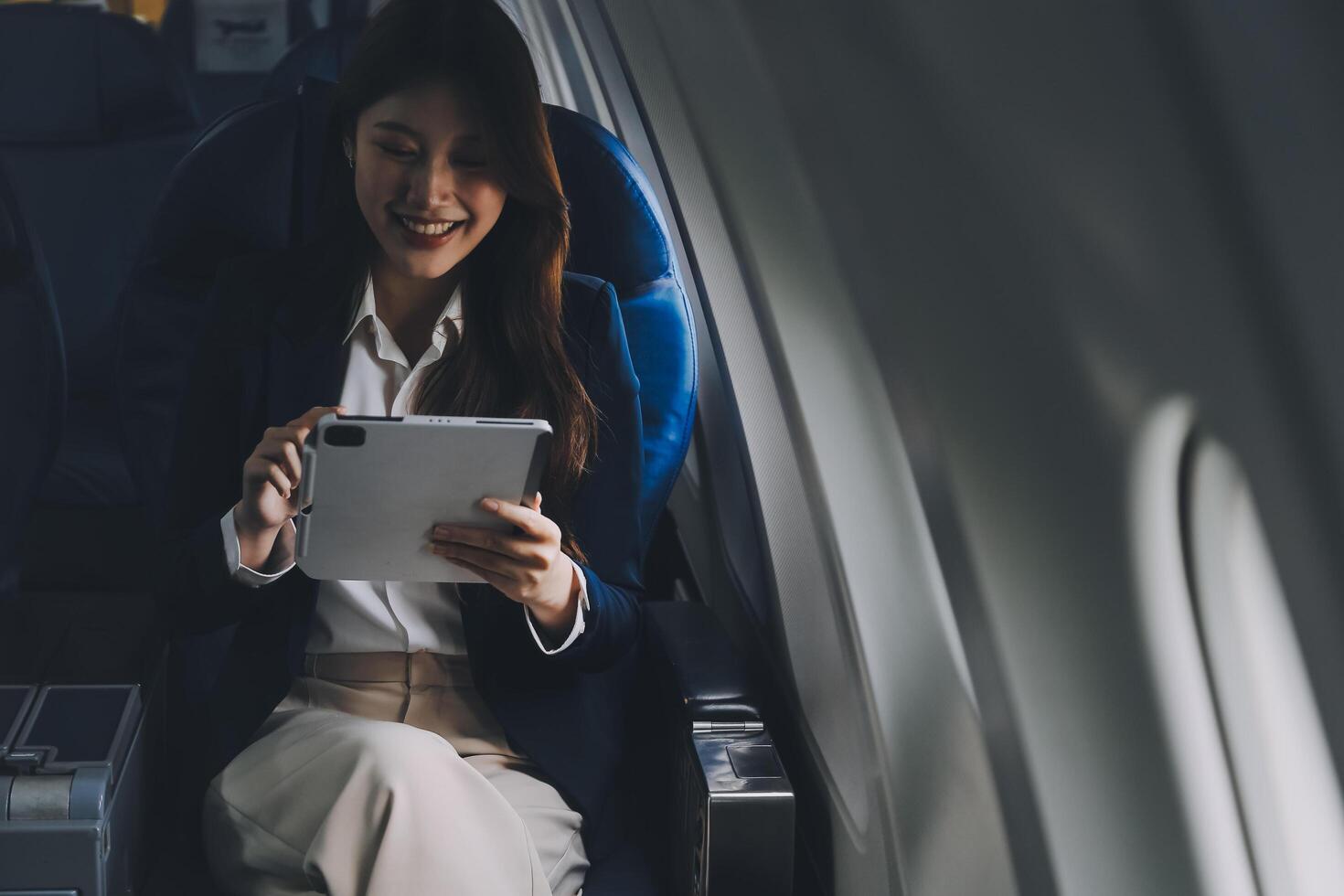 Young Asian executive excels in first class, multitasking with digital tablet, laptop and smartphone. Travel in style, work with grace. photo