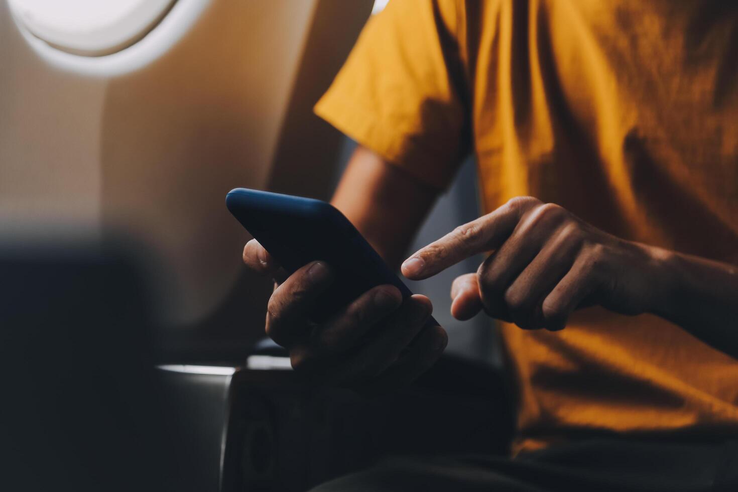 Attractive Asian businesswoman traveling on airplane playing with mobile phone while sitting in cabin. photo