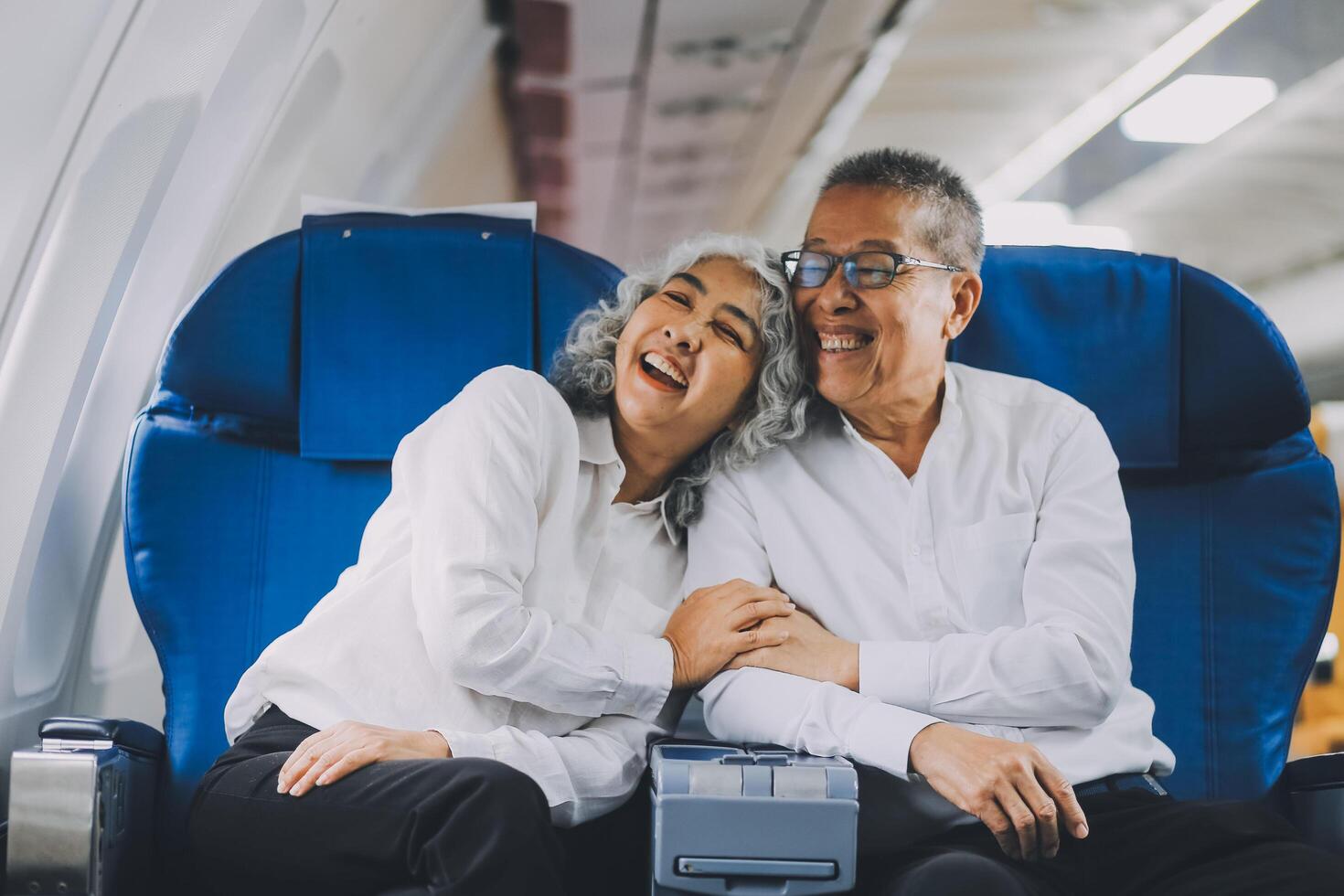 A mature couple enjoys a plane ride sitting near the window. They looked out into the sky. Immerse yourself in the scenery and excitement of the journey. To create precious memories together photo