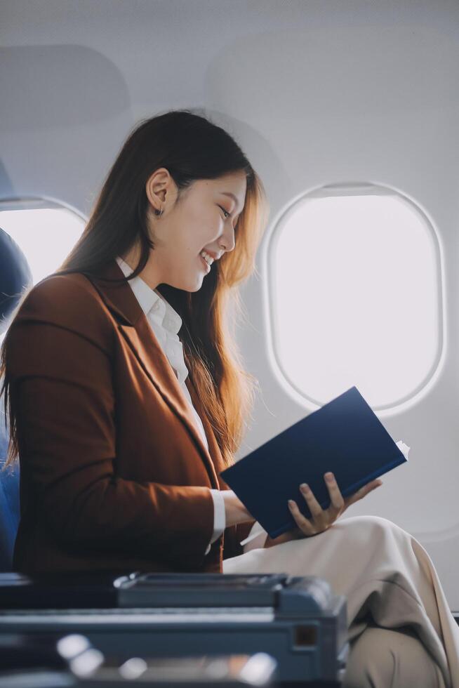 Young Asian executive excels in first class, multitasking with digital tablet, laptop and smartphone. Travel in style, work with grace. photo