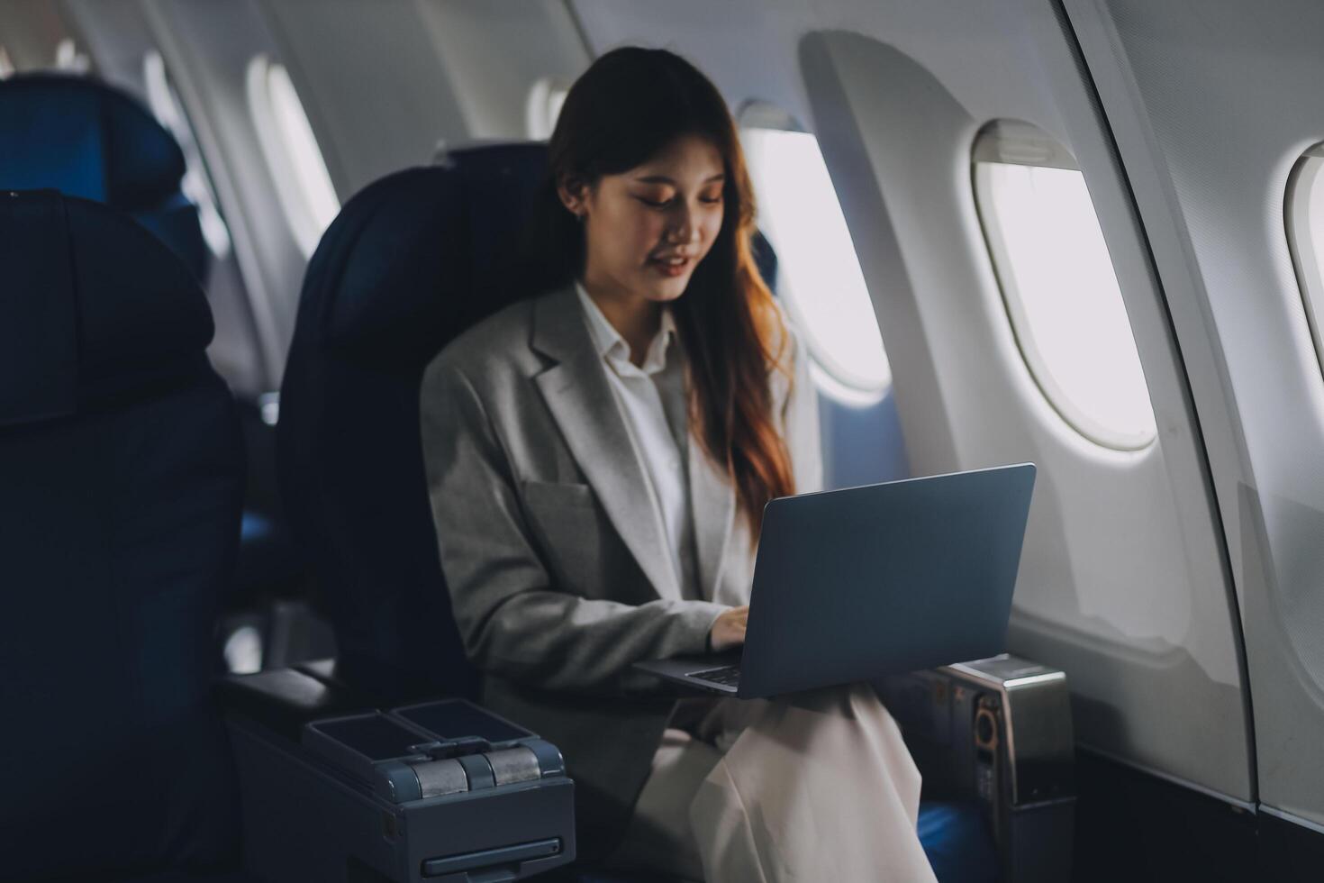 Joyful asian woman sits in the airplane and using tablet while go to travel photo