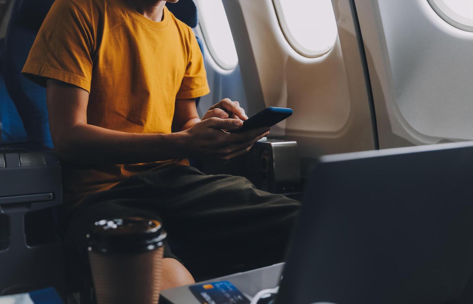 Attractive Asian businesswoman traveling on airplane playing with mobile phone while sitting in cabin. photo