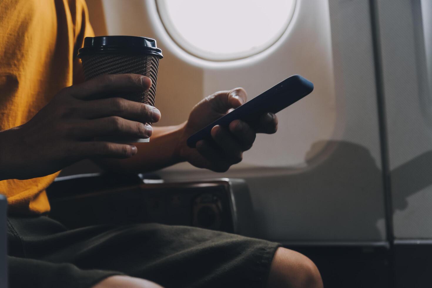 Attractive Asian businesswoman traveling on airplane playing with mobile phone while sitting in cabin. photo