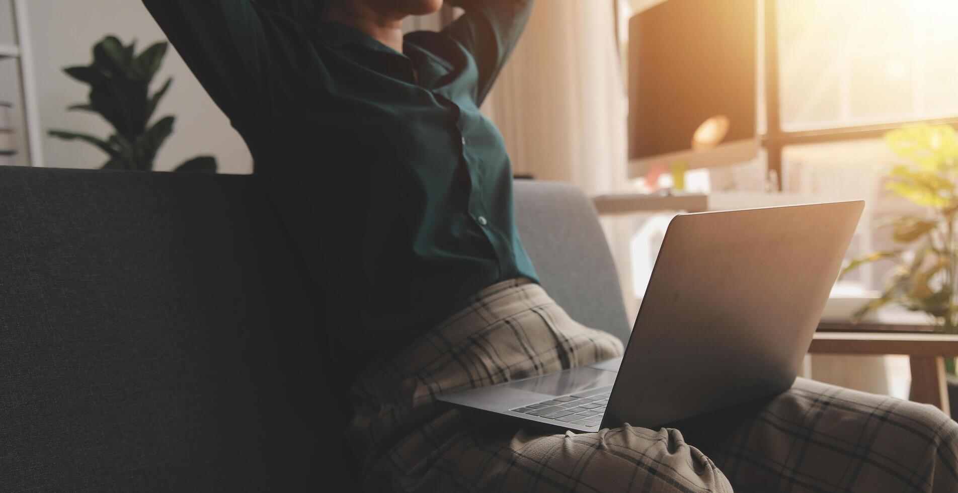 Distracted from work worried young woman sitting on couch with laptop, thinking of problems. Pensive unmotivated lady looking at window, feeling lack of energy, doing remote freelance tasks at home. photo