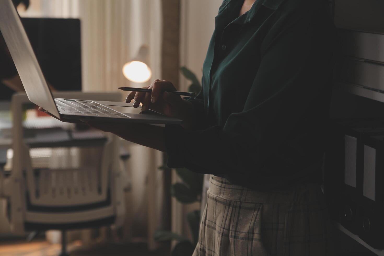 Female Manager Using Laptop Computer To Check Inventory. In the Background Warehouse Retail Center with Cardboard boxes, e-Commerce Online Orders, Food, Medicine, Products Supply. Over the Shoulder photo