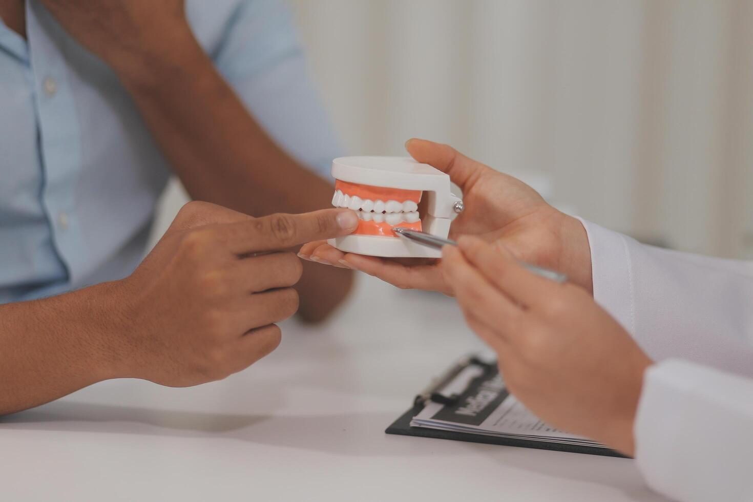 Dentist consultation - patient visit at the dental clinic office. Female dentist wearing dentures to explain teeth Recommend guidelines for orthodontics Dentist giving advice on patient's condition photo
