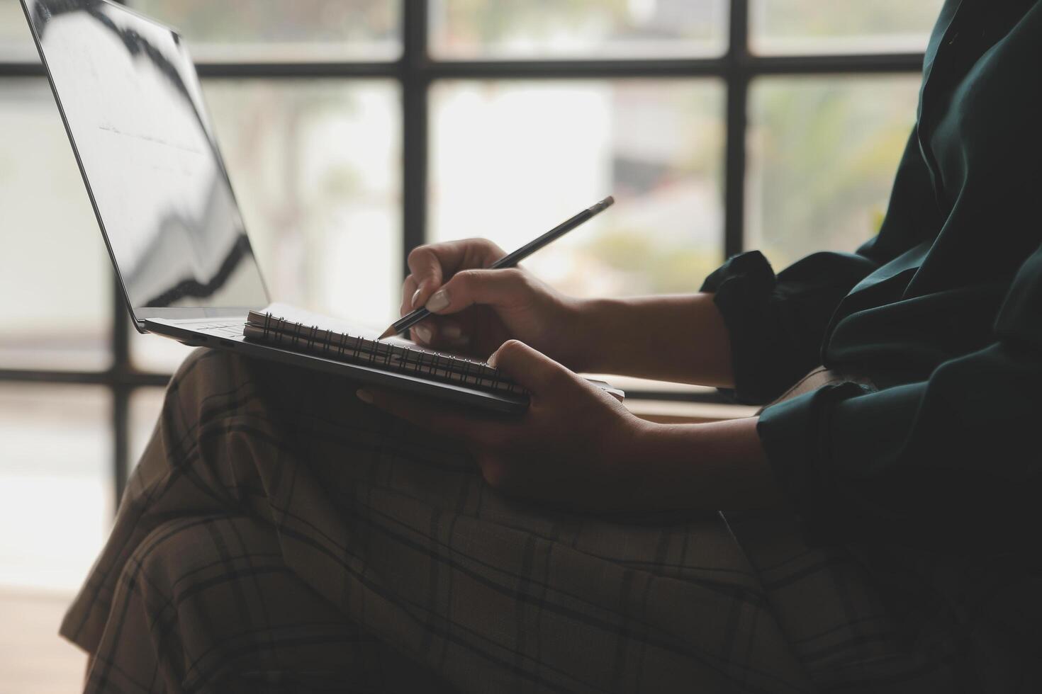 Distracted from work worried young woman sitting on couch with laptop, thinking of problems. Pensive unmotivated lady looking at window, feeling lack of energy, doing remote freelance tasks at home. photo