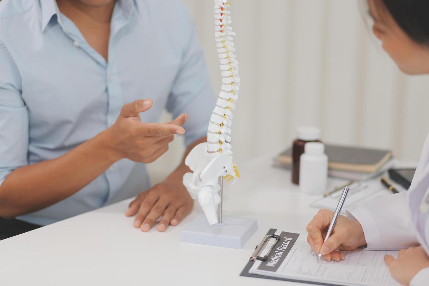 Orthopedists holding digital tablet and pointing at model. Concept of osteoporosis, back pain, lumbar, chiropractic and health. photo