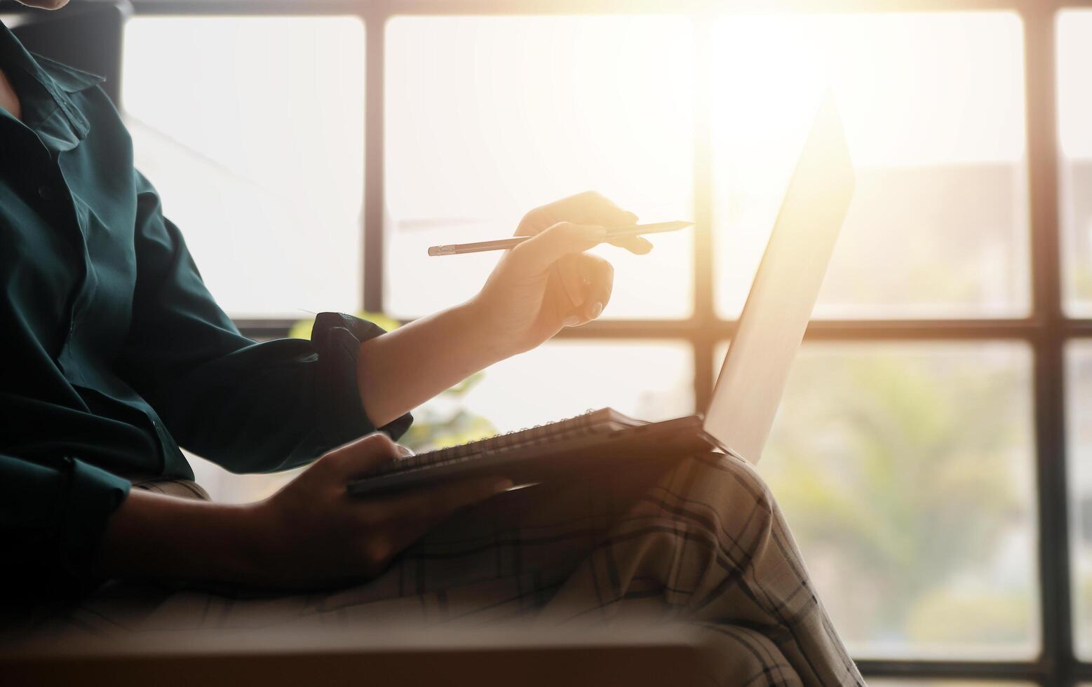 Distracted from work worried young woman sitting on couch with laptop, thinking of problems. Pensive unmotivated lady looking at window, feeling lack of energy, doing remote freelance tasks at home. photo