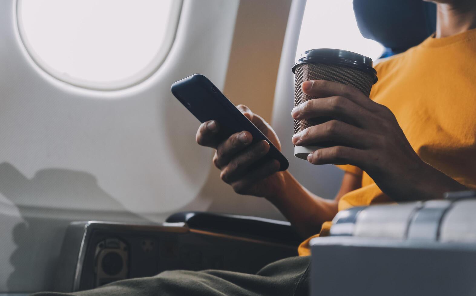 Attractive Asian businesswoman traveling on airplane playing with mobile phone while sitting in cabin. photo