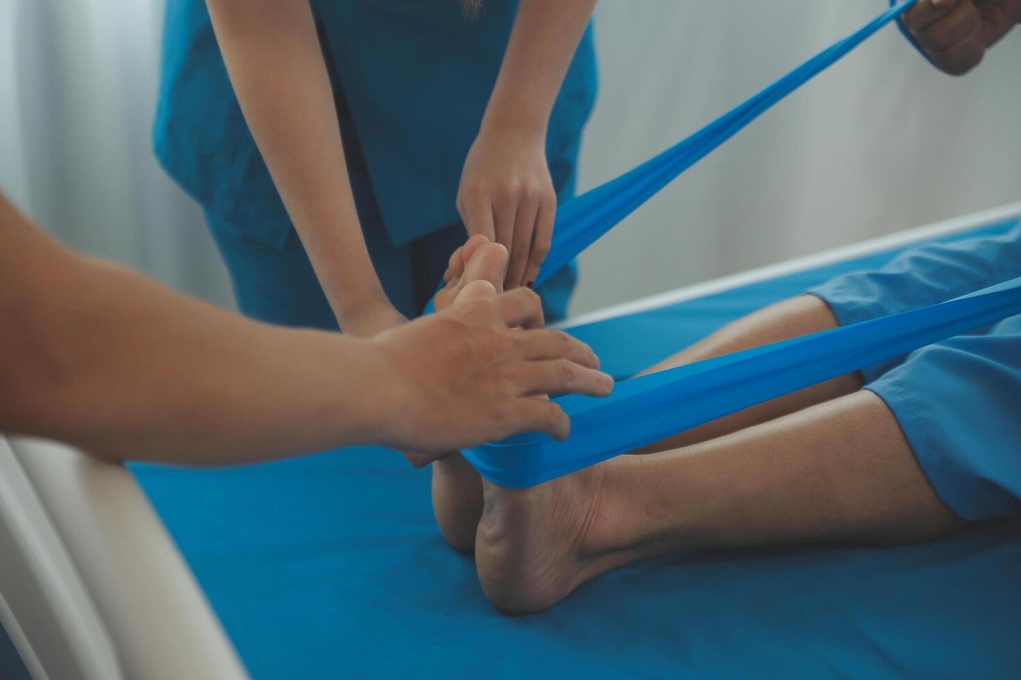 Professional orthopedist examining the little patient's leg in the clinic. Patient at the physiotherapy doing physical exercises with his therapist photo