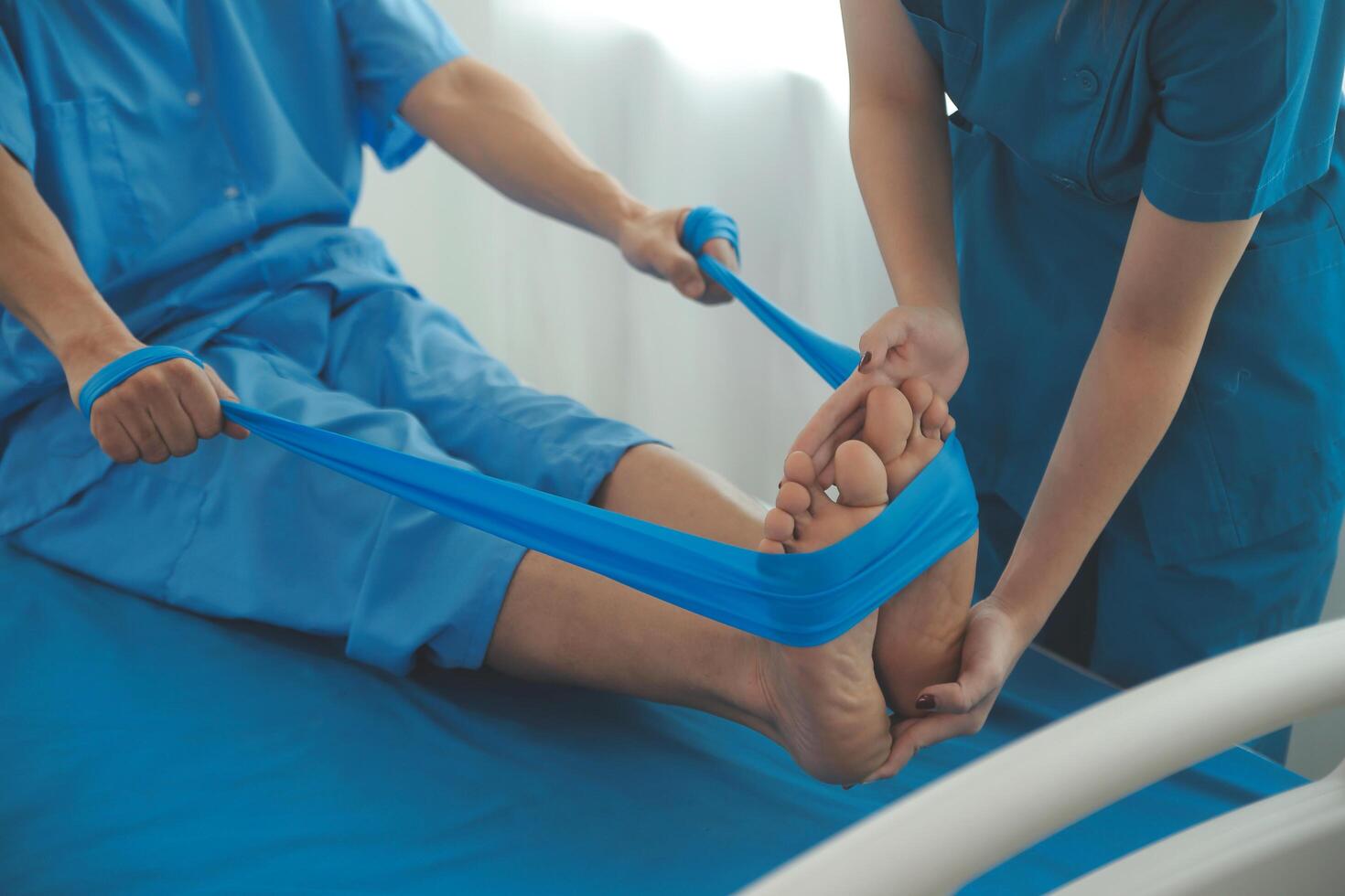 Professional orthopedist examining the little patient's leg in the clinic. Patient at the physiotherapy doing physical exercises with his therapist photo