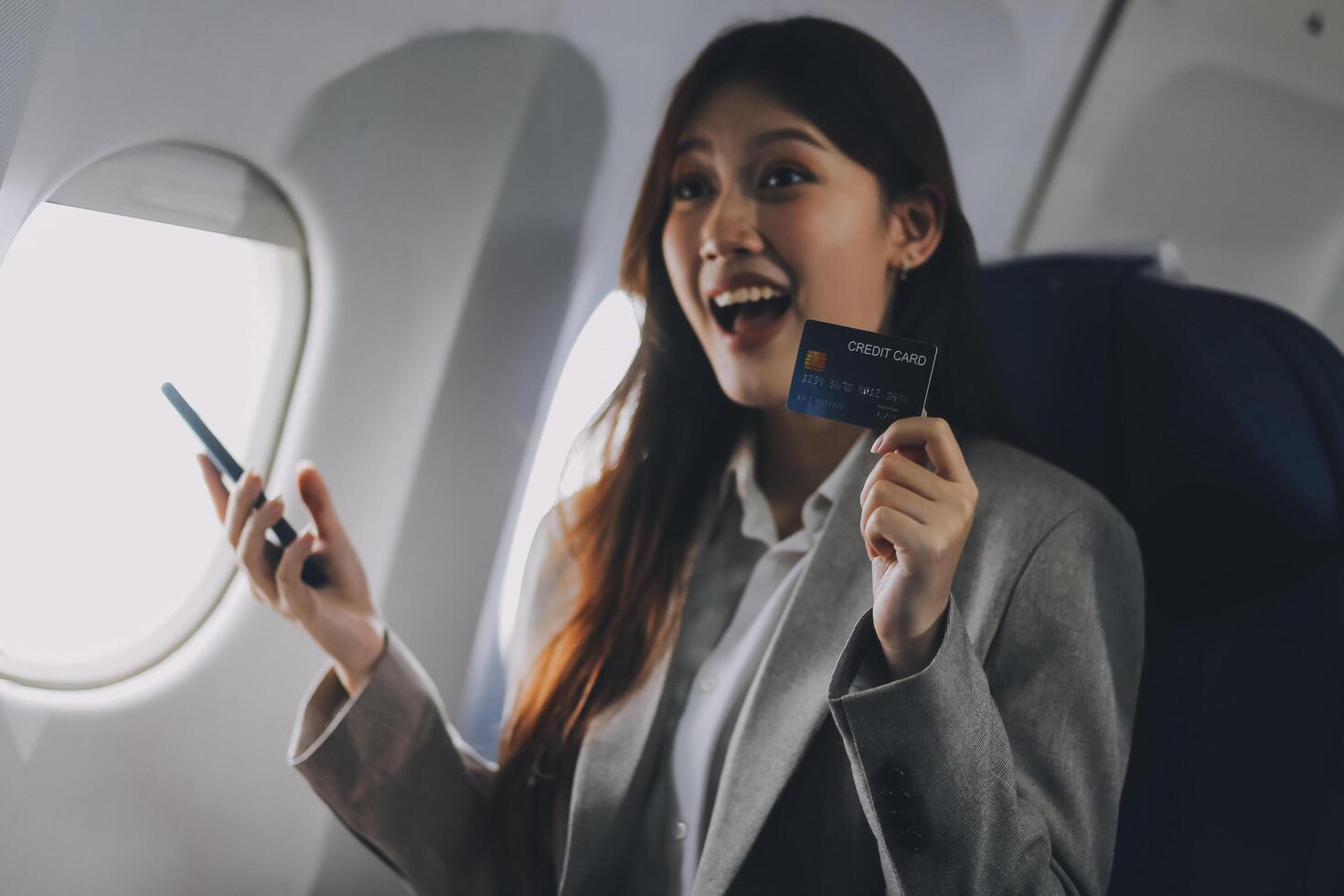 Young businesswoman holding credit card near blurred devices in private plane photo