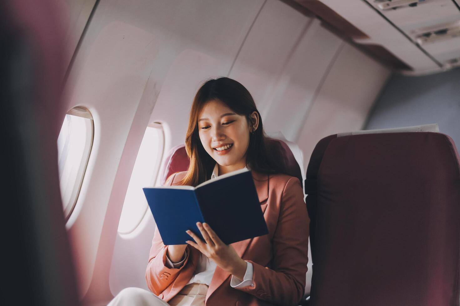 Attractive Asian female passenger of airplane sitting in comfortable seat while working laptop and tablet with mock up area using wireless connection. Travel in style, work with grace. photo