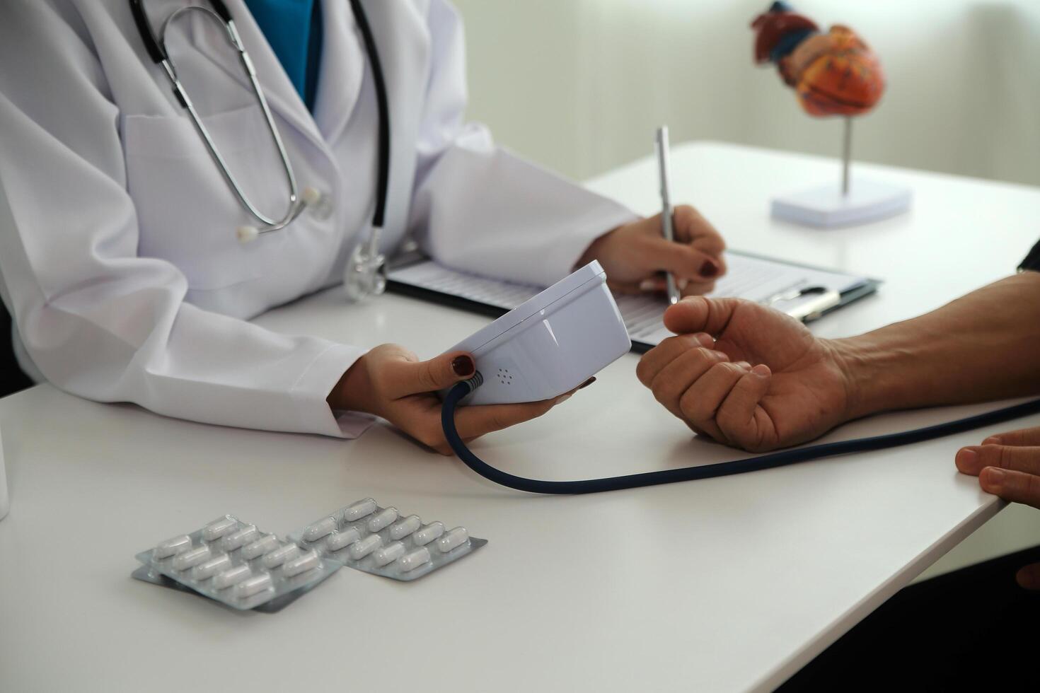 Doctor using sphygmomanometer with stethoscope checking blood pressure to a patient in the hospital. photo