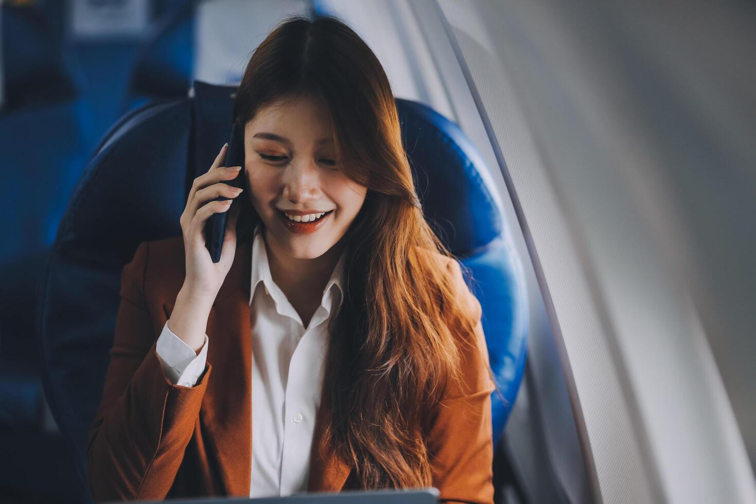 Young Asian executive excels in first class, multitasking with digital tablet, laptop and smartphone. Travel in style, work with grace. photo